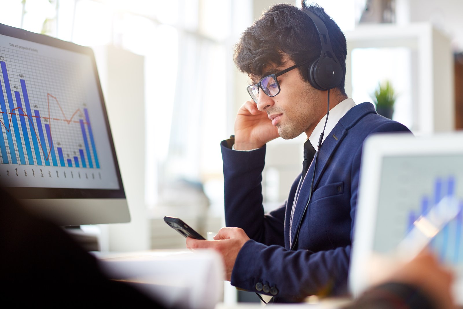 Client relations specialist with a headset reviewing portfolio charts